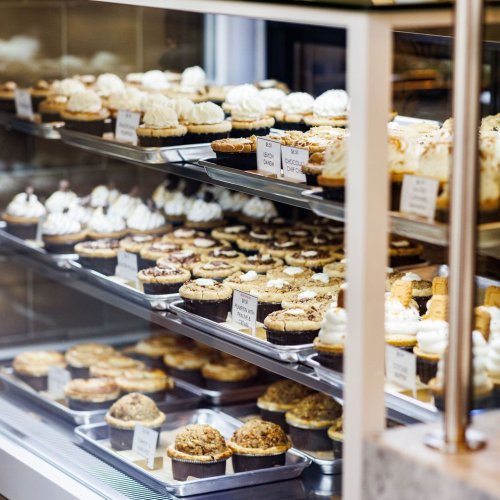 A display case filled with various cupcakes and pastries, showcasing an array of flavors and toppings.