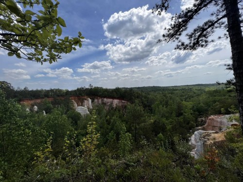 A scenic view of a lush green landscape with cliffs under a partly cloudy sky.