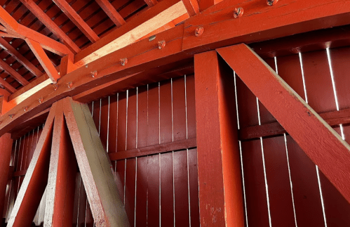 Close-up of a wooden structure with red beams and vertical slats, showcasing a rustic interior design.