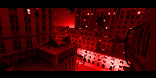 A surreal cityscape bathed in red light, featuring shadowy figures on rooftops and a dramatic, ominous atmosphere.