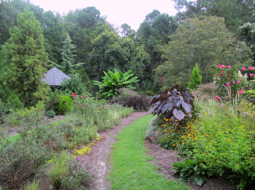 A lush garden path winding through vibrant flowers and greenery, with a gazebo in the background.