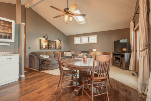 Cozy living space featuring a sectional sofa, dining table, and large windows with natural light.