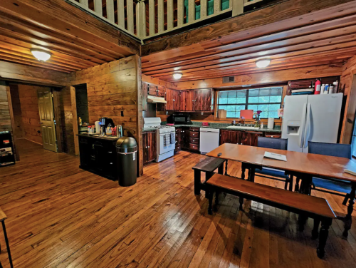 A spacious wooden kitchen with a dining table, appliances, and a cozy, rustic atmosphere.