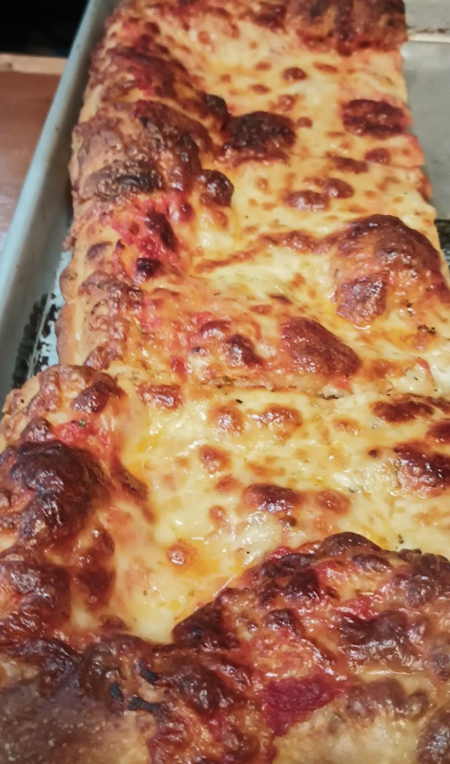 A close-up of a rectangular cheese pizza with a golden, bubbly crust and melted cheese on top.