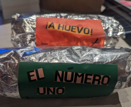 Two foil-wrapped burritos with colorful labels: one red labeled "¡A HUEVO!" and one green labeled "EL NÚMERO UNO."