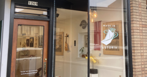 Exterior of a shop labeled "Made in Astoria," featuring large windows and a welcoming entrance.