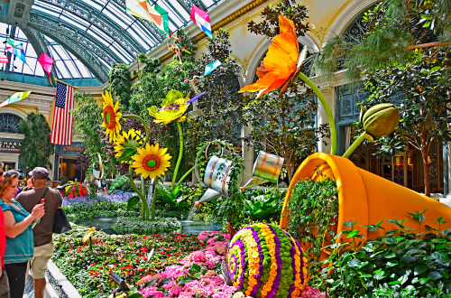 A vibrant indoor garden display featuring oversized flowers, colorful plants, and whimsical decorations.