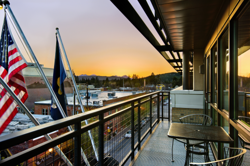 A balcony view at sunset, featuring American flags and distant mountains over a town.
