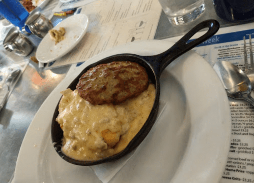 A cast iron skillet with sausage and creamy biscuits, served on a white plate with a menu in the background.