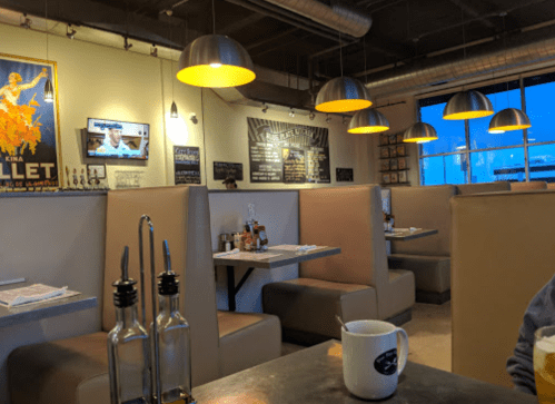 Cozy restaurant interior with booths, warm lighting, and decor on the walls, featuring a coffee cup on the table.
