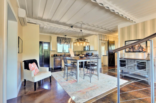 Bright, modern kitchen and dining area with a table, chairs, and stylish decor, featuring wooden floors and natural light.