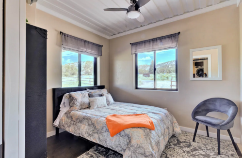 Cozy bedroom with a double bed, a chair, and large windows overlooking a scenic view.