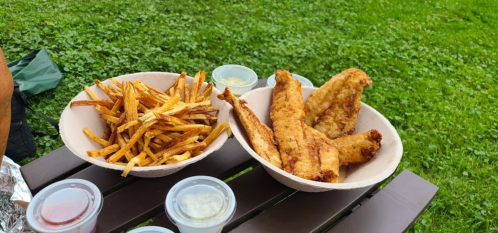 Two bowls of food: one with golden fries and the other with crispy fried fish, accompanied by dipping sauces.