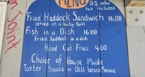 Menu board featuring fried haddock sandwich, fish in a dish, hand-cut fries, and house-made sauces. Prices listed.