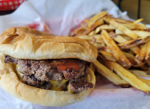 A juicy cheeseburger with bacon on a bun, served with a side of crispy French fries.
