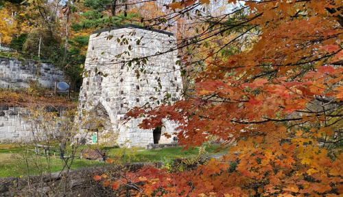 Stone structure surrounded by vibrant autumn foliage in shades of orange and yellow.
