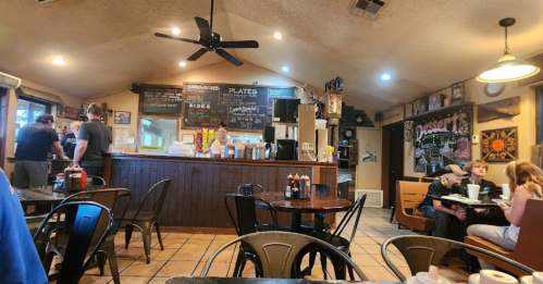 A cozy diner interior with a counter, tables, and patrons enjoying meals. Walls decorated with menus and art.