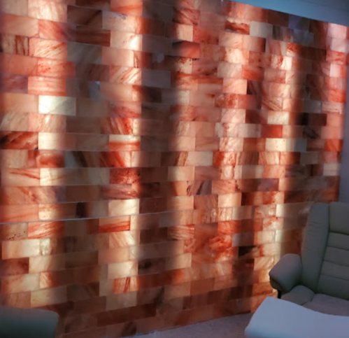 A textured wall made of illuminated salt blocks in warm tones, creating a cozy ambiance.