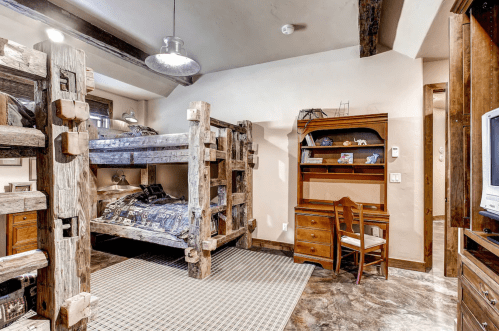 Cozy bedroom featuring a wooden bunk bed, desk, and rustic decor in warm tones.