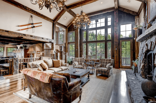 Spacious rustic living room with high ceilings, large windows, and cozy furniture, featuring a stone fireplace.