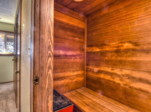 A wooden sauna interior with benches and a heater, featuring warm, natural wood tones and soft lighting.