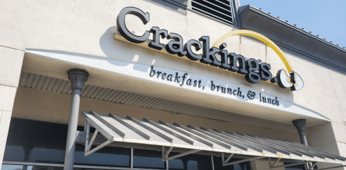 Sign for "Crackings" restaurant featuring breakfast, brunch, and lunch options, with a modern awning.