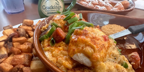 A hearty meal featuring a cheesy dish with green onions, alongside crispy potatoes and a side of beignets.