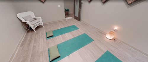 A serene yoga studio with two mats, a chair, and soft lighting, creating a calming atmosphere for practice.