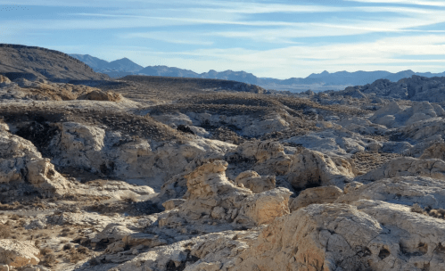 A vast desert landscape with rocky formations and distant mountains under a clear blue sky.