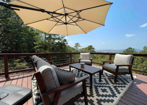 A cozy outdoor seating area with a large umbrella, overlooking a scenic view of trees and mountains.