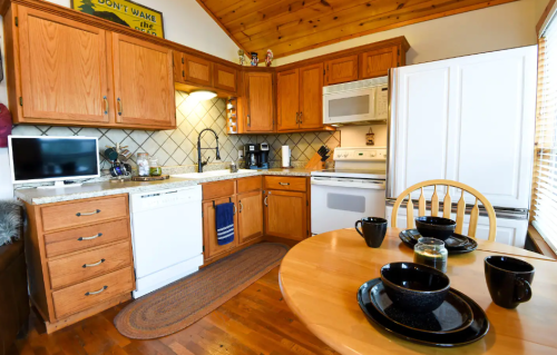 Cozy kitchen with wooden cabinets, granite countertops, and a dining table set for four. Modern appliances included.
