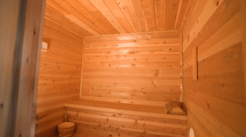 Interior of a wooden sauna with smooth, light-colored wood paneling and a bench along the wall.
