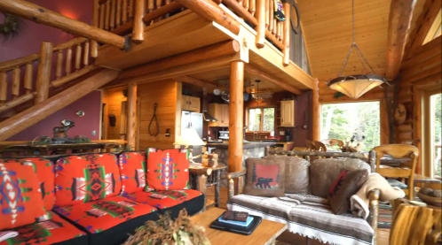 Cozy log cabin interior with wooden beams, colorful seating, and a warm, inviting atmosphere.