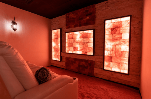 A cozy room with three illuminated salt wall panels and a plush seating area, creating a warm ambiance.