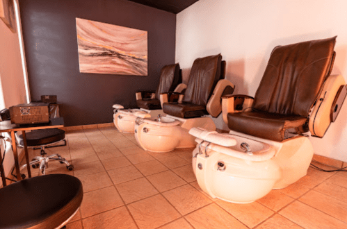 A serene nail salon with three pedicure chairs and a modern painting on the wall.