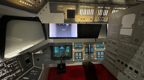 Interior of a spacecraft cockpit featuring control panels, screens, and various instruments.
