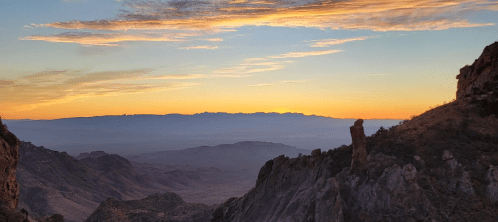 A stunning sunset over a mountainous landscape, with vibrant orange and yellow hues illuminating the sky.