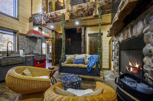 Cozy cabin interior featuring a stone fireplace, wooden beams, and comfortable seating with natural decor.