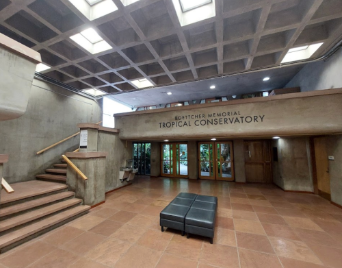 Interior of the Boettcher Memorial Tropical Conservatory, featuring a spacious entrance and seating area.