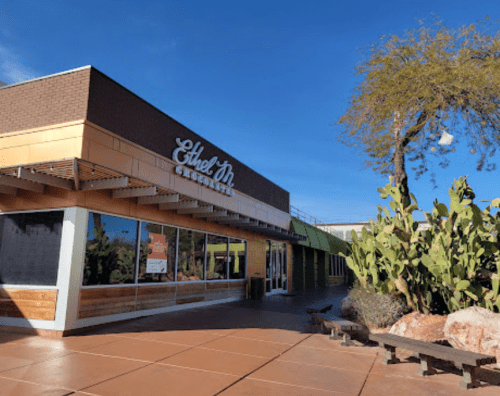 Exterior of Ethel M Chocolates store with a clear blue sky and cacti in the foreground.
