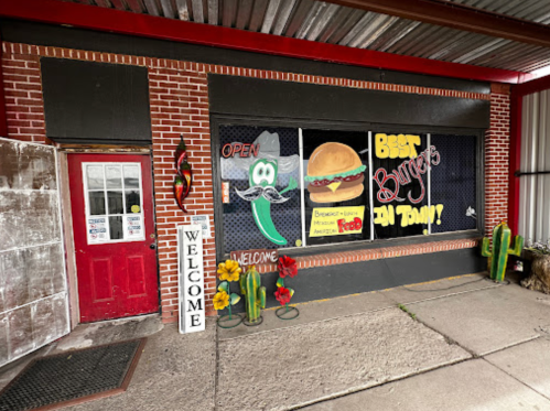 A colorful restaurant exterior featuring a "Best Burgers" sign, open door, and decorative plants.