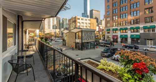 View from a balcony overlooking a city street with the Ohio House building and skyscrapers in the background.