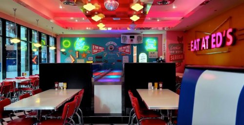 Colorful diner interior with neon signs, retro decor, and red seating, creating a vibrant atmosphere.