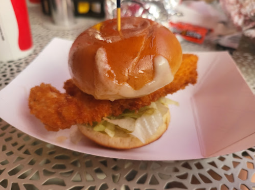 A crispy chicken sandwich with lettuce on a soft bun, served in a paper tray.