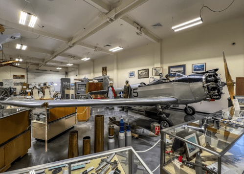 A vintage aircraft displayed in a museum, surrounded by various aviation artifacts and exhibits.