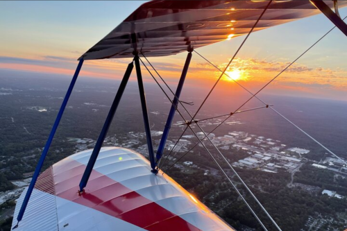 View from an airplane wing at sunset, showcasing a colorful sky and landscape below.