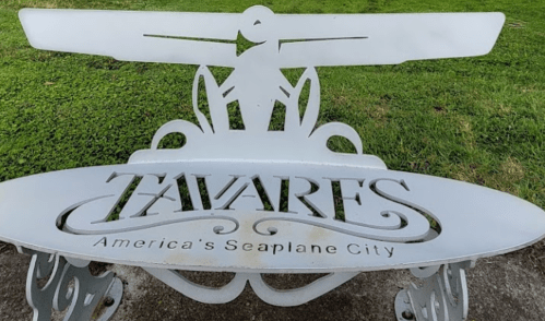 A decorative bench with the inscription "Tavares, America's Seaplane City" and a seaplane design.