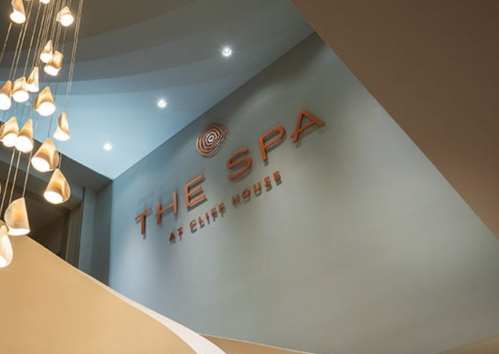 Sign for "The Spa at Cliff House" displayed on a wall, with modern lighting fixtures above.