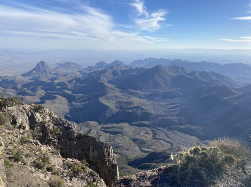 A panoramic view of rugged mountains and valleys under a clear blue sky, showcasing natural beauty and vast landscapes.
