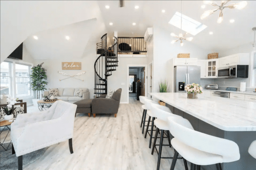 Bright, modern open-concept living space with a spiral staircase, cozy seating, and a stylish kitchen.